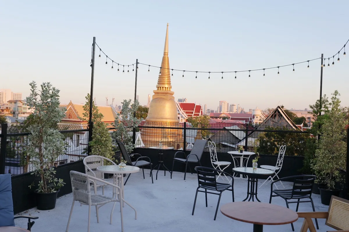 The Bud Brew terrace in Bangkok at golden hour, with the gold spire of the Golden Mount behind it.